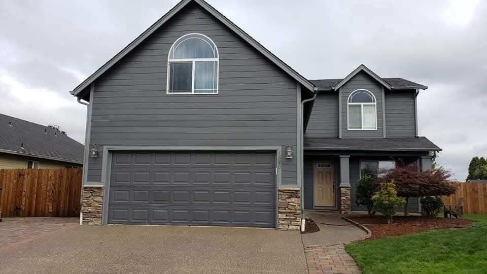 Slate grey home with arched windows and a stone-clad garage base