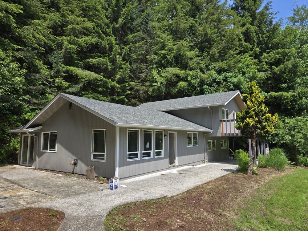 Grey ranch home repainted against a wooded hillside