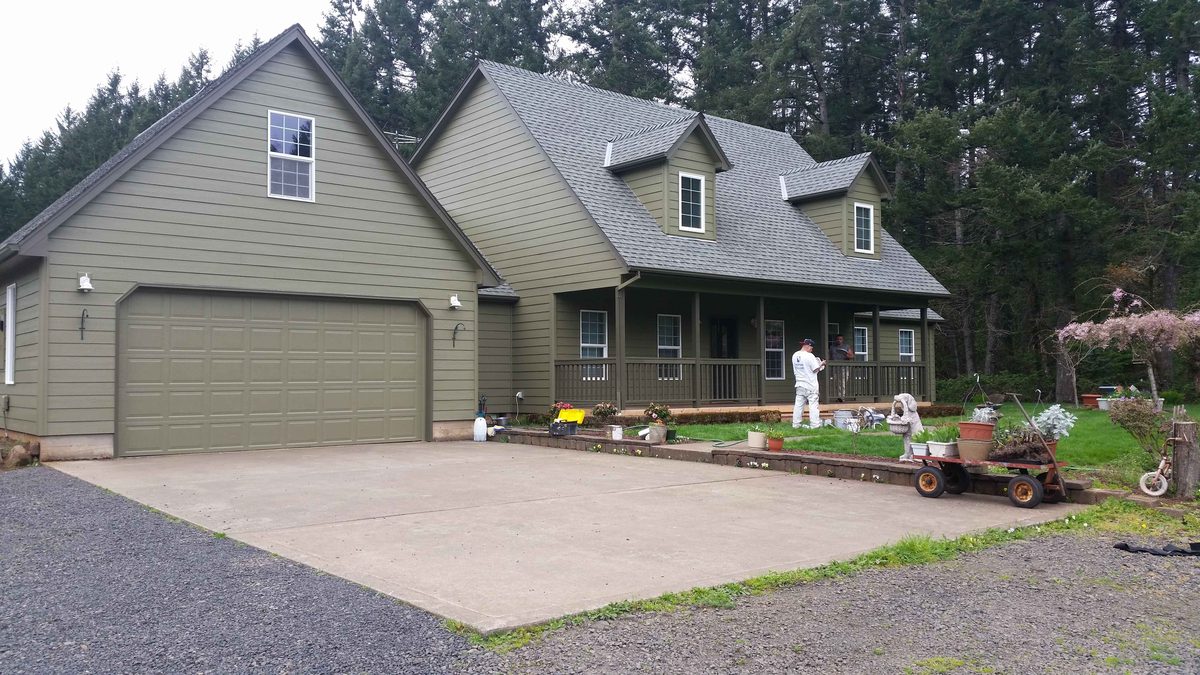 Olive green farmhouse with a wraparound porch, newly painted