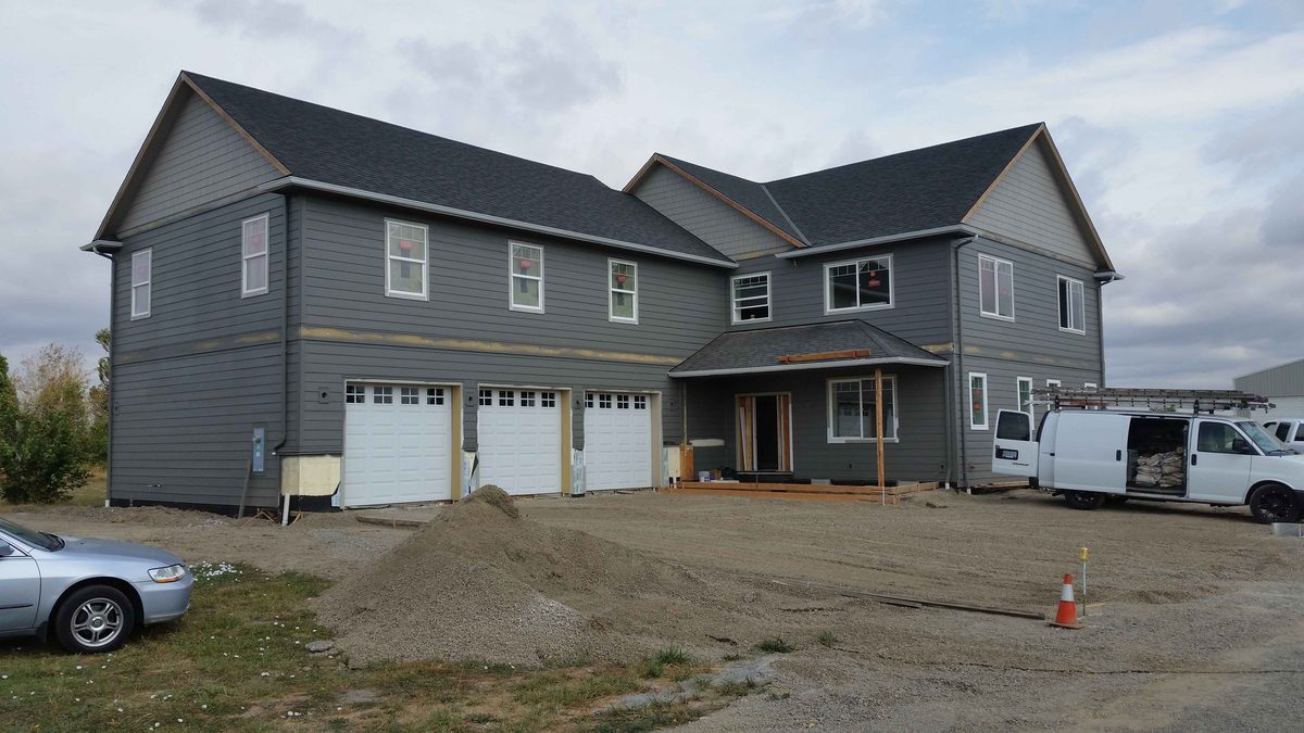 Dark grey new-build home with a three-car garage