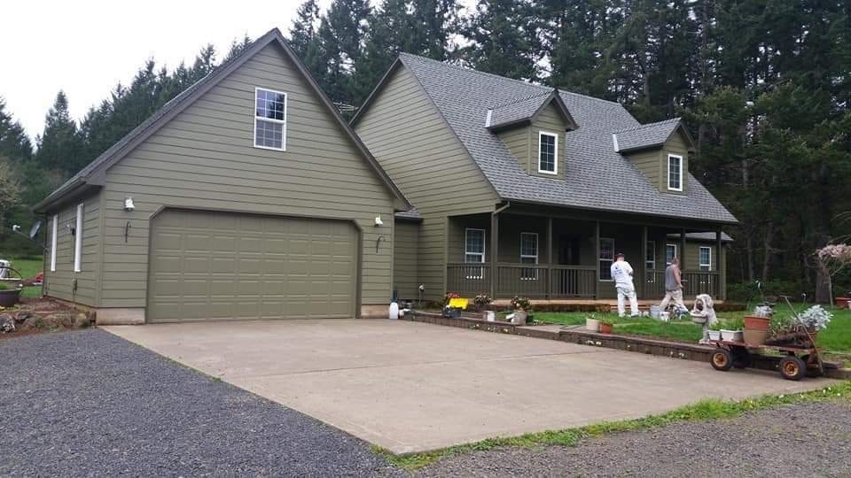 Olive green home and garage with the crew still on site