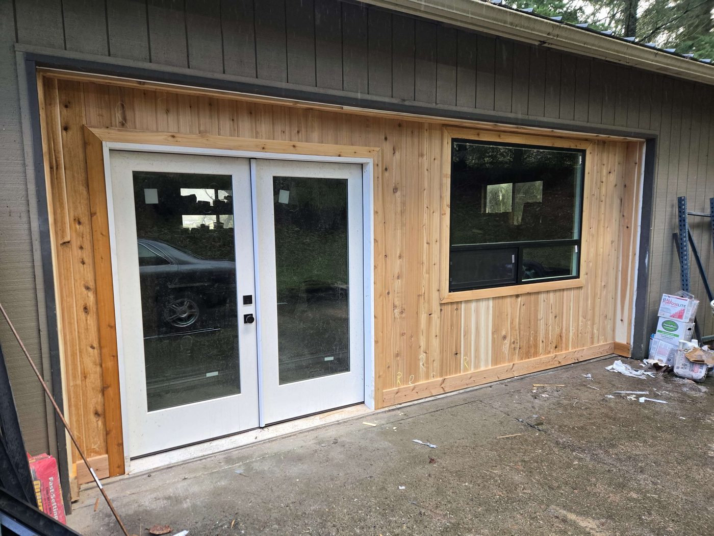 New cedar-clad addition with double glass doors and a picture window