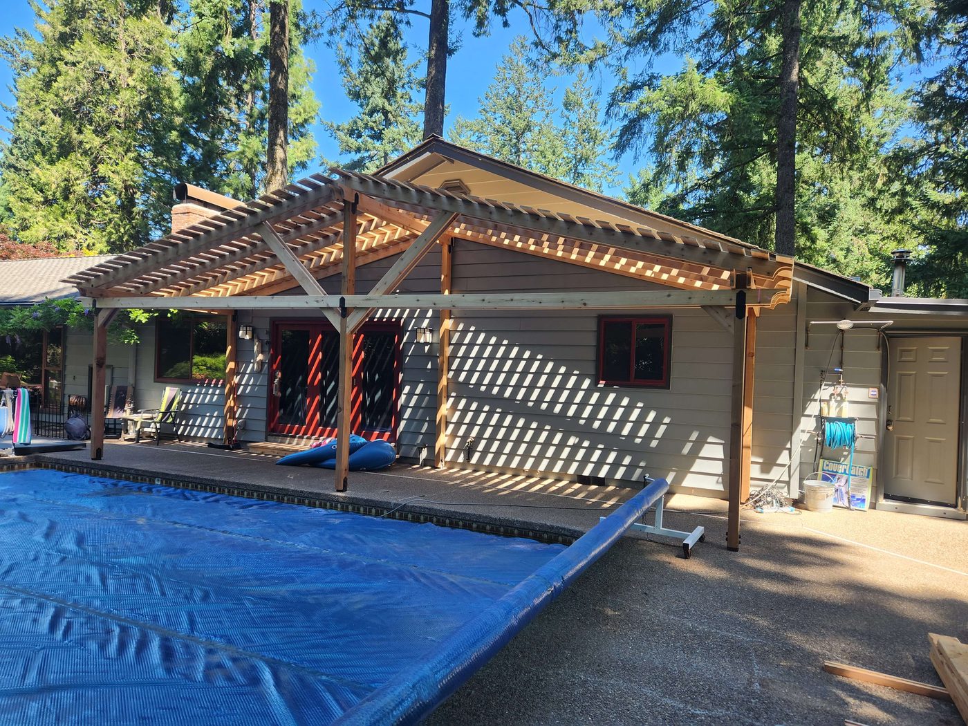 Finished cedar pergola shading a patio beside a pool